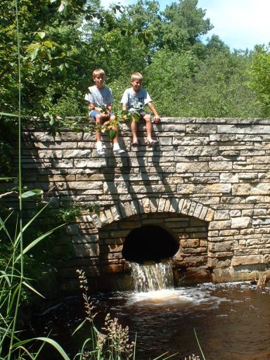 2 boys sitting on the stone bridge over Fisher Creek