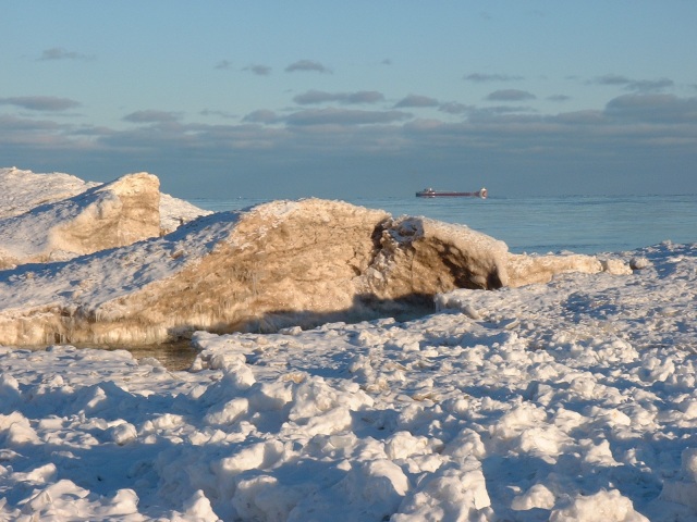 Large ship on horizon passing by natural ice and sand sculpture