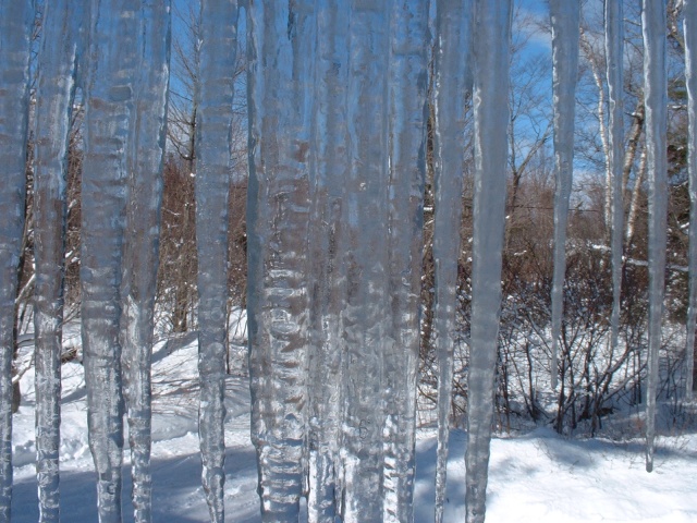 Long icycles hanging from the eaves, snow and blue sky beyond